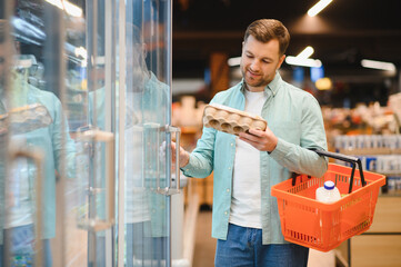 Customer opening refrigerator door choosing eggs in supermarket