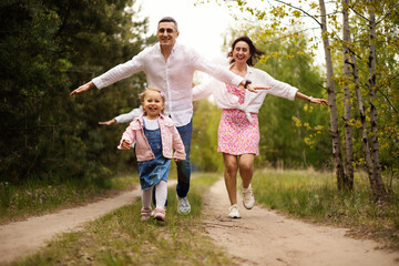 Obraz premium Parents playing with their little daughter in the park