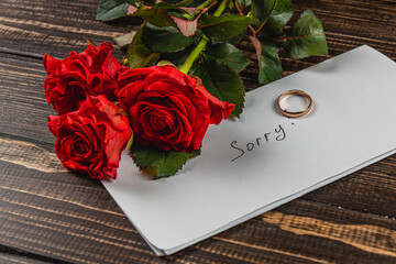 Broken engagement with red roses and a heartfelt apology note on the table