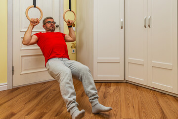 Man performs pull-ups on gymnastic rings indoors