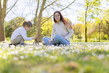Mother and son building a small teepee in a field of daisies
