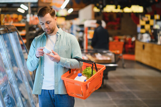 Customer choosing groceries in supermarket reading product label