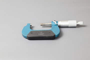A blue micrometer isolated on grey background, A micrometer is a tool to precisely measure the...