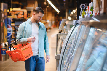 Obraz premium Customer choosing products in refrigerated section of supermarket