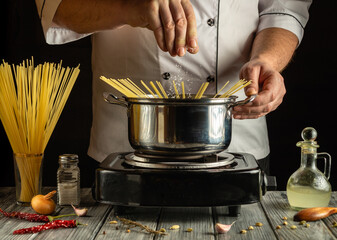 A chef expertly prepares pasta by adding spaghetti to boiling water in a stainless steel pot....