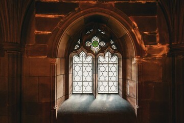 Fototapeta premium Beautifully detailed arched window with stained glass in a historic stone building.