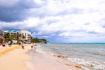 Tropical Caribbean beach people parasols fun Playa del Carmen Mexico.