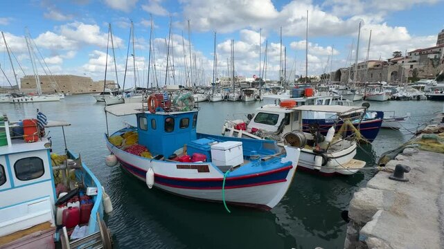 Boat station at the port of Heraklion, Crete, with various small boats moored along the docks. A typical Mediterranean harbor scene reflecting the maritime culture and daily life of the island.