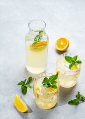 Fresh lemonade with lemon, mint and ice. Two glasses of citrus mojito on a light background