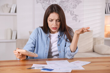 Paying bills. Woman with calculator and invoices at wooden table indoors