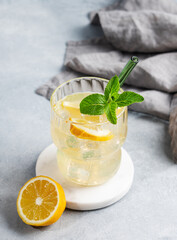 Fresh drink lemonade with lemon, mint and ice in glass on a light background with napkin.