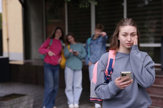 Teenage girl with smartphone suffering from bullying at school, selective focus - Powered by Adobe