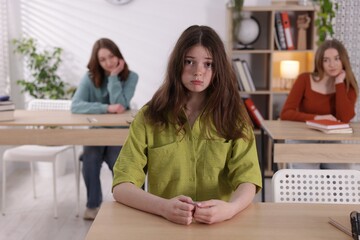Bullying. Upset teenage girl at desk in school