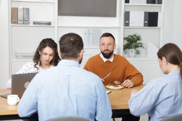 Fototapeta premium Colleagues eating and chatting during lunch break in office