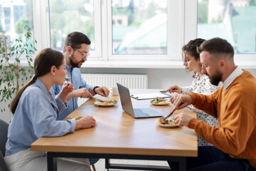 Colleagues eating and chatting during lunch break in office