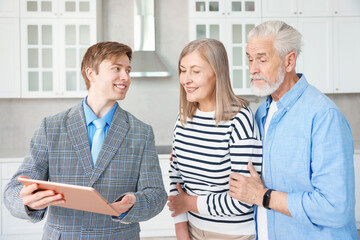 Smiling real estate agent with tablet working with couple in kitchen
