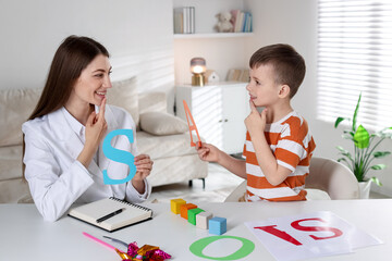 Speech therapist working with little boy indoors