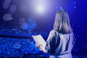 Woman performing on stage of concert hall crowded with people