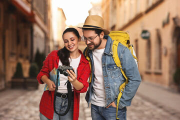 Happy tourists with backpack and camera on city street