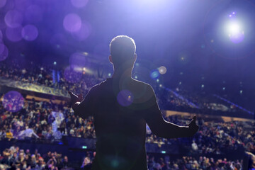 Man performing on stage of concert hall crowded with people