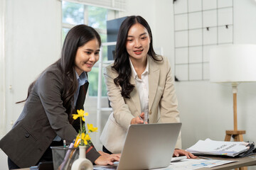 Business Collaboration and Teamwork. Two professionals discussing project data on a laptop.