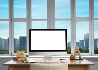 Fototapeta premium Workplace with modern computer near city view window in office
