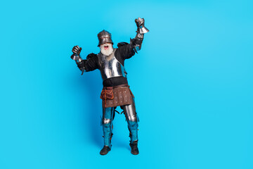 Mature Man in Medieval Knight Armor Celebrating Joyfully Against Blue Background