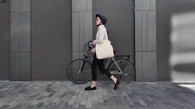 Woman holding eco bag or cotton tote bag in the city while riding a bike