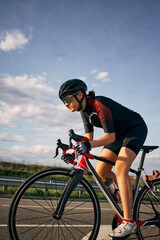 Dynamic side view photo of cyclist in aerodynamic posture gripping handlebars, highlighting bike...