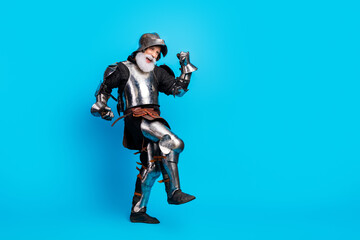 Naklejka premium Senior man in medieval knight armor posing against blue background