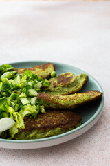 Zucchini and broccoli pancakes served with a mixed salad of cucumbers, young peas, and radishes. This healthy vegetarian dish is both delicious and nutritious