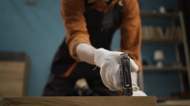 male carpenter using pneumatic gun assembling furniture at home. Joiner male worker working with pneumatic staple gun