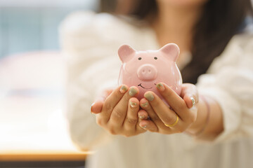 Close-up view of a woman holding a piggy bank. Save money and make investments or create a personal...