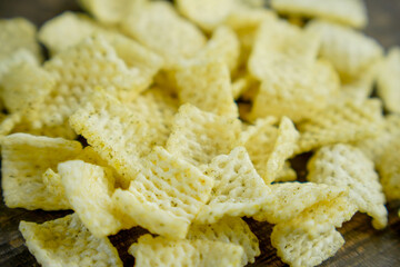 full screen view of hollow net chips with a sprinkling of fine spices on a wooden table. hollow net chips on wooden table surface.