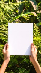 Sunny day scene with hands holding a white book outdoors