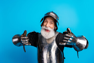 Elderly man in medieval armor smiling with a fun and jovial demeanor against a vibrant blue...