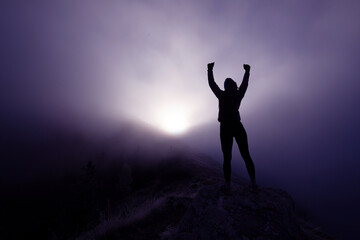 Woman Celebrating at Mountain Summit.Woman celebrating on rocky mountaintop with arms raised in...