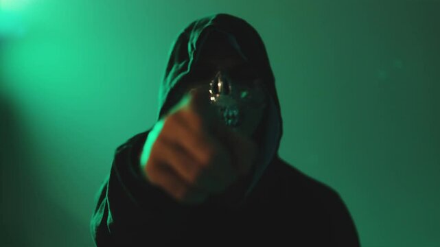 Anonymous person in mask and hoodie pointing camera