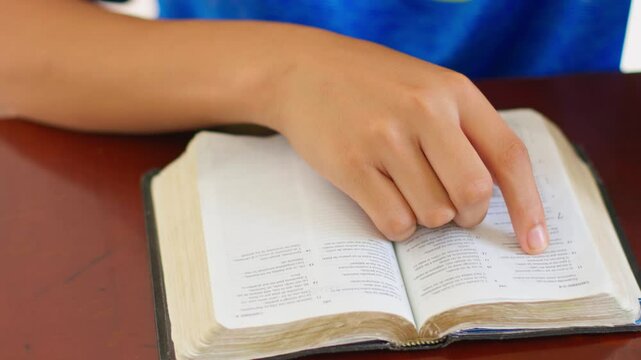 A person is pointing at a book with their finger