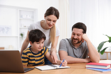 Fototapeta premium Parents helping their son with homework at wooden table indoors