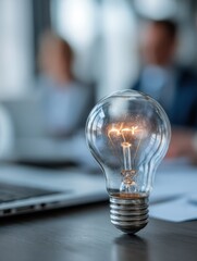 Close up of lightbulb on desk in office setting representing idea generation and teamwork in a modern environment