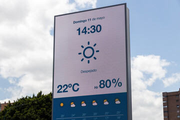 Digital weather display shows current temperature, humidity, and forecast with sunny icon against a...