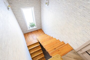 high-angle shot of wooden stairs, a window with a plant, and textured walls.