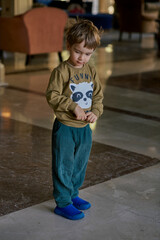 Little caucasian boy is playing in the hotel lobby by himself.
