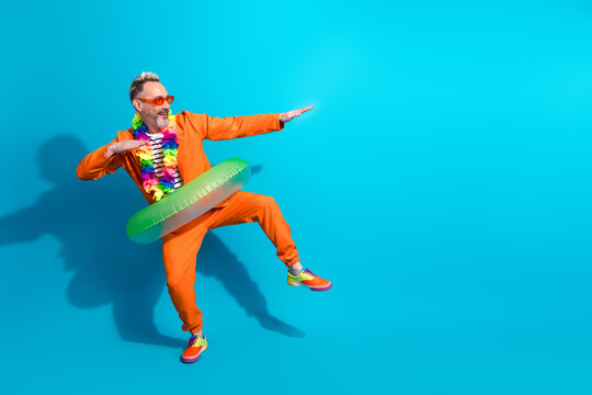 Fun spirited man in orange suit with tropical accessories posing against a vibrant blue background inspiring humor and positivity