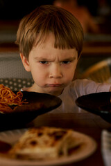 Frustrated little boy's portrait at the dinner table.