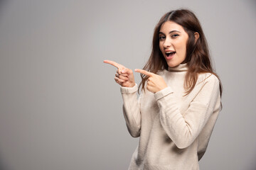 Pretty cheerful woman gesturing with fingers and showing away