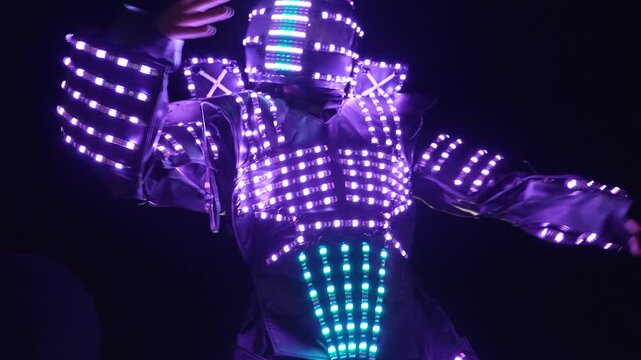Performer in illuminated LED costume dancing at night in closeup