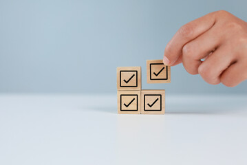 Achieve business goals and success. Complete work. Wooden cube with check mark icon. Organization...