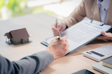 Real estate agent with documents to buy new house of house plan and keys on table. At table with...